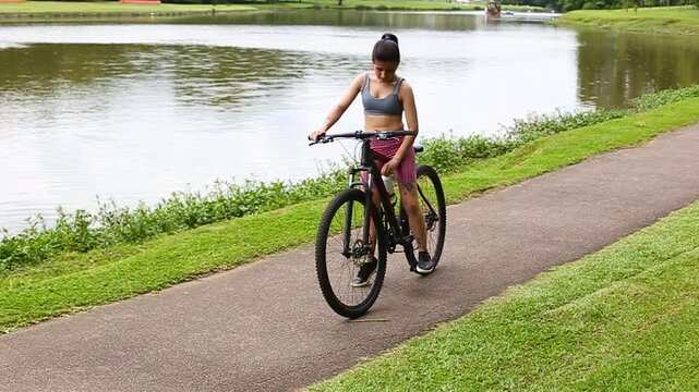 Young woman biking and making a stop to drink water