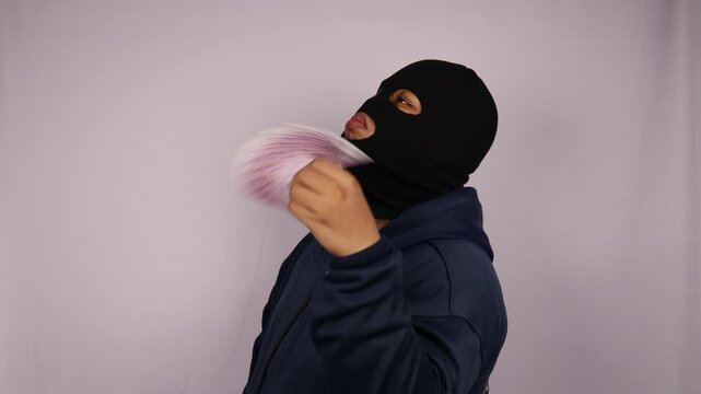 close up on the thief fanning his face using bundles of 500 euro banknotes and wearing jacket with a white background
