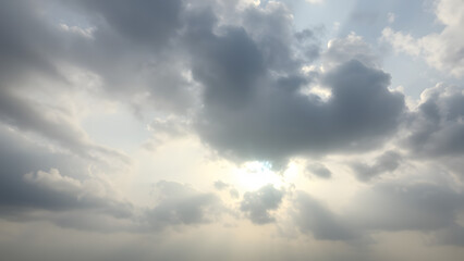 Obraz premium A cloudy sky with dramatic gray clouds against a backdrop of pale blue and faint sunlig