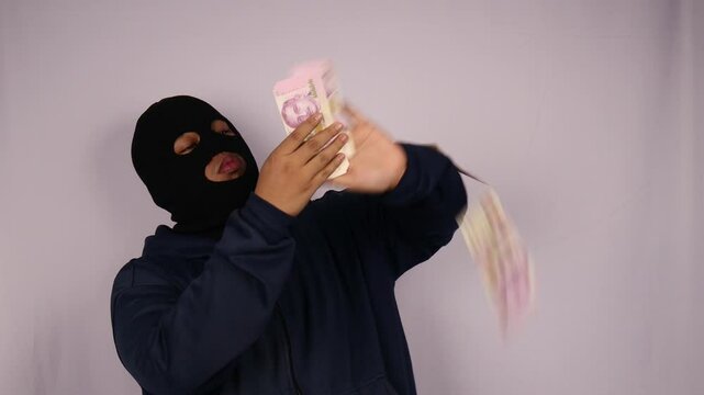 close up on the thief fanning out his bundles of ten thousand banknotes and wearing a jacket with a white background.
