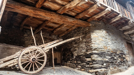 Obraz premium Old wooden cart resting under rustic balcony in ancient village