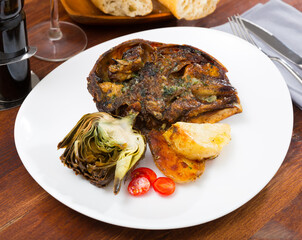 Spanish dish - lamb head with artichoke, tomatoes and potatoes. High quality photo