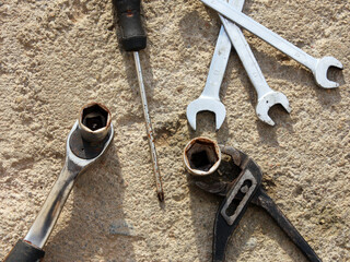 Mechanic's tools: screwdriver, tongs, pliers, wrenches, horn wrenches on a concrete surface background. Industry and repair