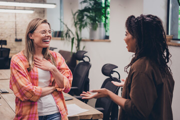 Photo of two ambitious businesswomen coworking chatting tell joke laugh modern loft interior office...