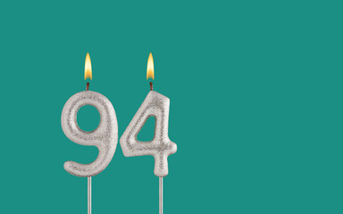 Birthday candle number 94 - Card on a green background.