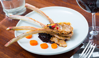 Baked lamb ribs with spicy sauce and carrots served at plate in cafe