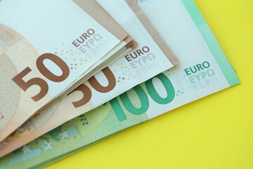 Big amount of one hundred and fifty euro money bills on yellow background