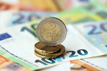 Two euro coin lies on huge amount of different euro dollars banknotes