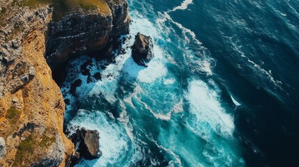 Aerial view of dramatic ocean waves crashing against rugged cliffs.