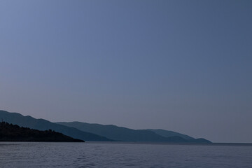 Gently hilly headland coming down to the sea, under a cloudless sky.