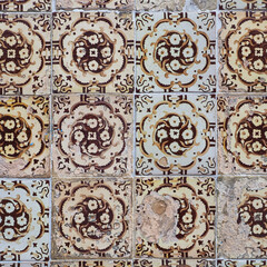 Damaged, dirty, not corrected, vintage azulejos, glazed ceramic tiles with brown ornaments on building wall. Heritage Concept of traditional Portuguese art. Decorative background for design.