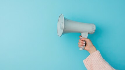 Hand Holding Gray Megaphone Against Solid Light Blue Background