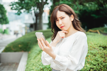 スマホを見て困る女性
