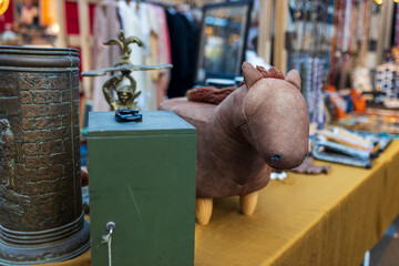 A leather horse on wooden legs stands on a table with various vintage items for sale at the  flea...