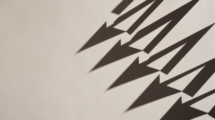 Abstract black shadows forming arrow shapes on a light-colored wall, creating a dynamic interplay of light and shadow.
