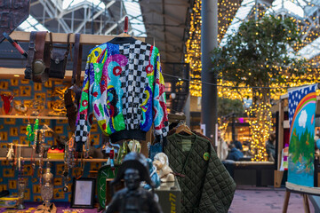 London, UK - November 22, 2024. Flea market at Spitalfields Market. Sequined jackets in 1980s style and leather belts on display for sale.