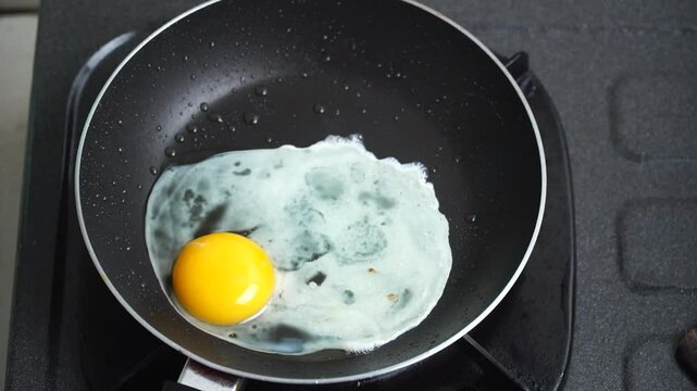 Woman's hands cracking eggs and frying them in a frying pan