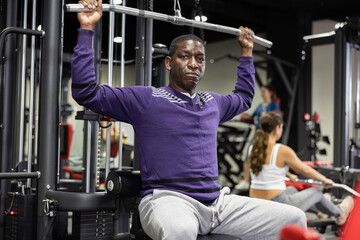 African american man is engaged in a simulator for the development of back muscles