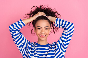 Photo of pretty young girl arms hold hair wear striped pullover isolated on pink color background