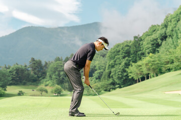ゴルフ場でアイアンショットを打つ男性ゴルファー
