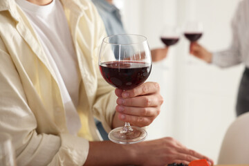 People with glasses of red wine indoors, selective focus