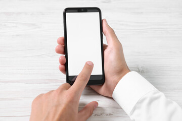 Man unlocking smartphone with fingerprint scanner at light wooden table, closeup