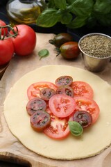 Raw galette with tomato and basil on wooden table, closeup