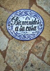 Talavera sign on stone wall. Bienvenido, Welcome sign