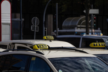 A group of German taxis with their iconic yellow roof signs lined up in an urban setting,...