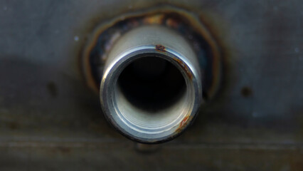 Close-up of an old metal pipe with a hole in it