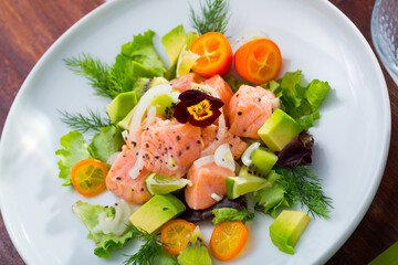 Delicious seafood ceviche from salmon on plate with cumquat, green dill and avocado