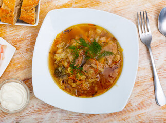 Soup of cabbage Shchi with pork and vegetables, served in bowl