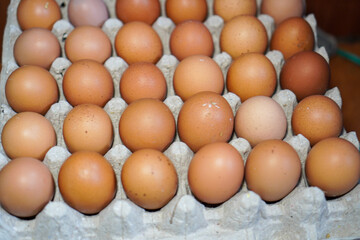 Close-up view of a carton filled with a dozen fresh brown eggs. A Dozen Brown Eggs in Cardboard Carton Background.