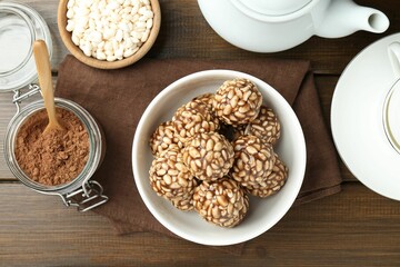 Tasty chocolate puffed rice balls served on wooden table, flat lay