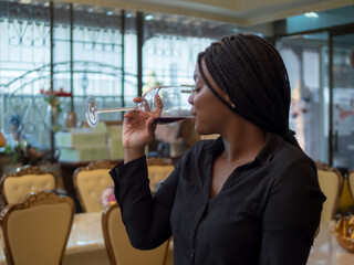 Portrait girl woman african one person celebrating smile happy enjoying people bar hand holding drink alcohol on glass wine and red wine bottle on dinner at party sitting in pub and restaurant cafe.