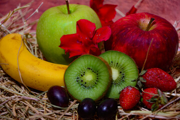 Fresh fruits neatly arranged on a table, featuring green and red apples, strawberries, bananas, and kiwi slices. The vibrant colors and natural textures create a refreshing look.