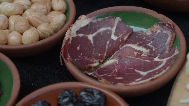 Deliciously Sliced Cured Meat Presented on a Rustic Plate, Accompanied by Tasty Extras