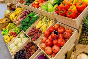 Fresh colorful fruits, vegetables are arranged neatly in wooden crates at busy market stall, attracting shoppers.