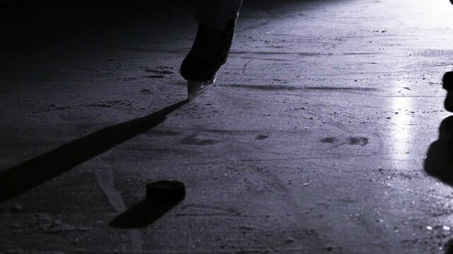 Hockey players practicing with shots dynamically lit on ice rink