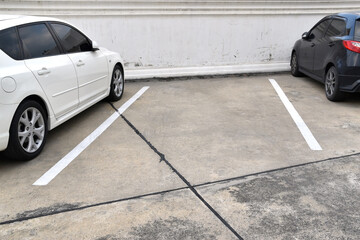 one parking lane empty between two parked cars, urban parking lot along grunge wall