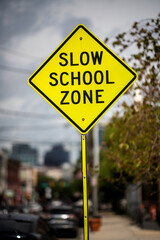 Bright Yellow Slow School Zone Sign on an Urban Street During the Day