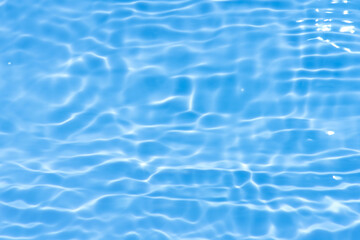 Blue water with ripples on the surface. Defocus blurred transparent blue colored clear calm water surface texture with splashes and bubbles. Water waves with shining pattern texture background.