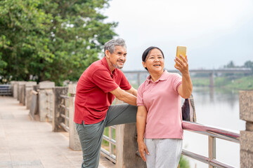 healthy asian senior couple exercising and relaxing on running walkway by the river in the city,elderly lifestyle,wellness,wellbeing