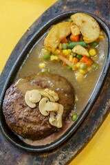 A close-up of a thick, juicy beef steak and fluffy roasted potatoes on a hot plate. The contrast between the red meat, golden potatoes, and green herbs creates a visually appealing dish.