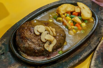 A close-up of a thick, juicy beef steak and fluffy roasted potatoes on a hot plate. The contrast between the red meat, golden potatoes, and green herbs creates a visually appealing dish.