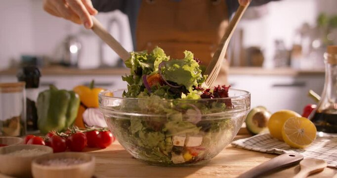 Closeup of a Fresh Mediterranean Salad Being Tossed and Mixed with Vibrant Vegetables in a Sunlit, Bright Kitchen