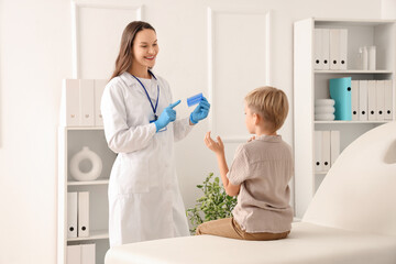 Fototapeta premium Female doctor with head lice comb and little boy with pediculosis in clinic