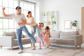 Happy family in headphones listening music and dancing at home