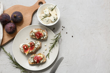 Plate of delicious fig bruschetta with ricotta and blue cheese on white background