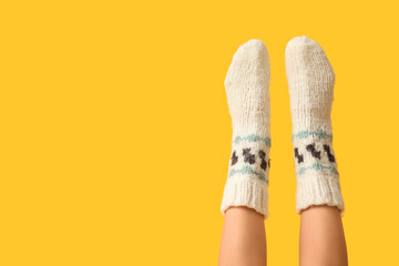 Legs of young woman in knitted socks on yellow background